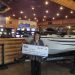 Person holding large check in front of boat they won
