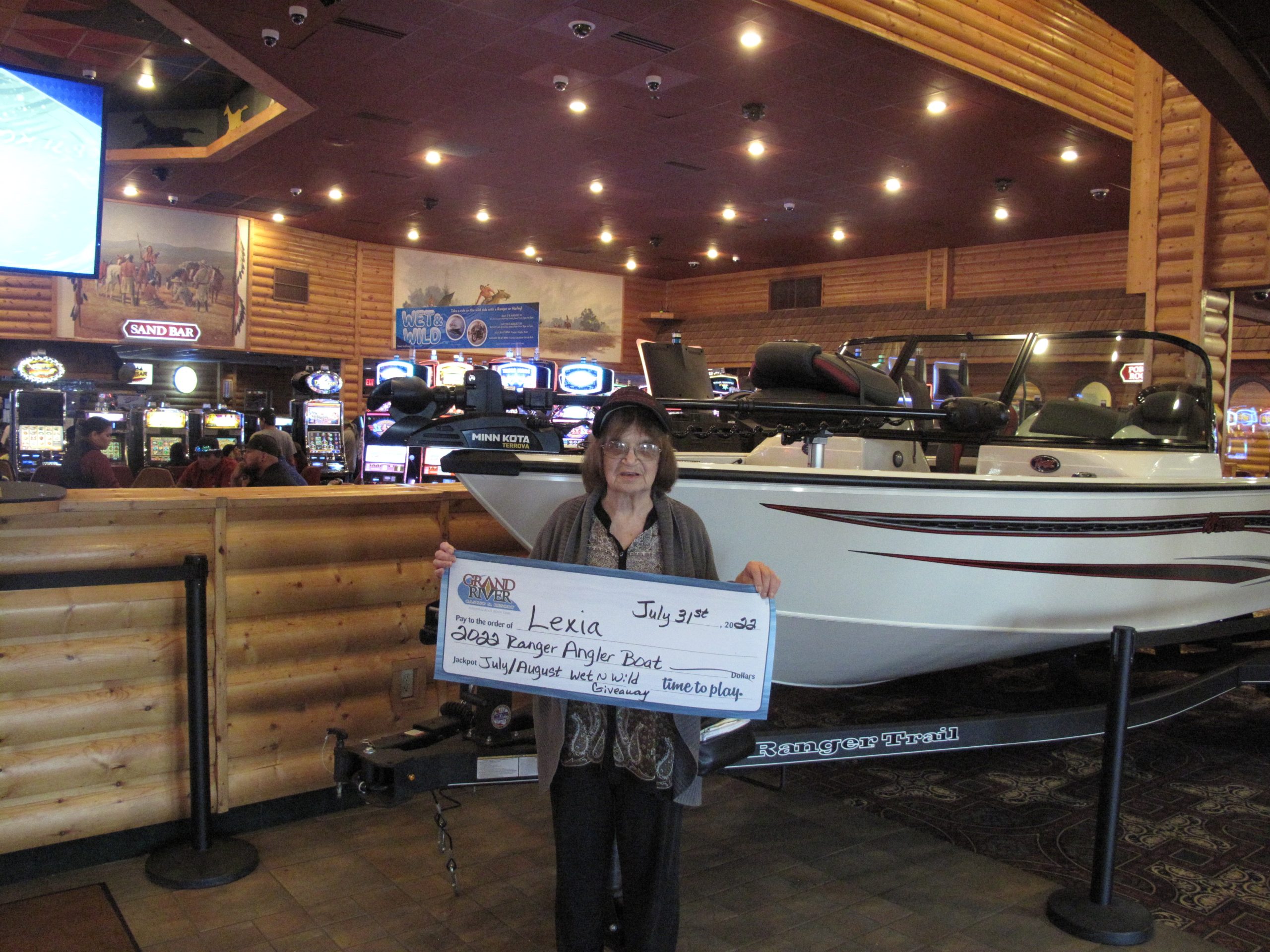 Person holding large check in front of boat they won