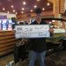 Photo of person holding an oversized check in front of boat prize